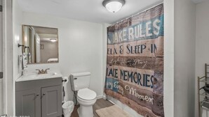 A bathroom with a white sink, toilet, and mirror. There is a wooden wall with motivational text. - Anglers Paradise (Dayton)