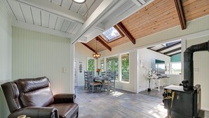 Ein geräumiger Wohnbereich mit Ledersessel, Esstisch mit Stühlen, Kamin und Dachfenster.