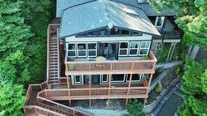 Ein mehrgeschossiges Haus mit einer Holzterrasse, einem Balkon und einer Treppe, die zu den oberen Stockwerken führt.