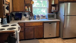 Una cocina con armarios de madera, un refrigerador de acero inoxidable, un horno empotrado y un ventanal que proporciona luz natural.