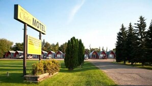 A motel with a signboard, multiple red-roofed cabins, and a well-maintained lawn. - The little chalet motel (Brandon)
