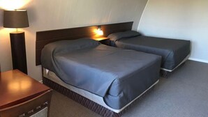A hotel room with two beds, a nightstand, and a lamp. - The little chalet motel (Brandon)
