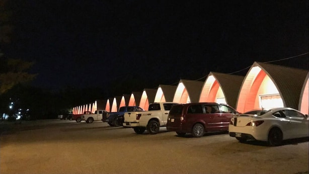 A row of tents with vehicles parked in front. - The little chalet motel (Brandon)