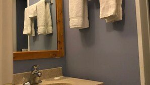 A bathroom with a sink, mirror, and two towels hanging on the wall. - The little chalet motel (Brandon)
