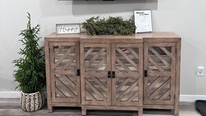 A wooden cabinet with a mounted TV above it, a small potted plant, and a welcome sign. - Home In Eddyville (Eddyville)