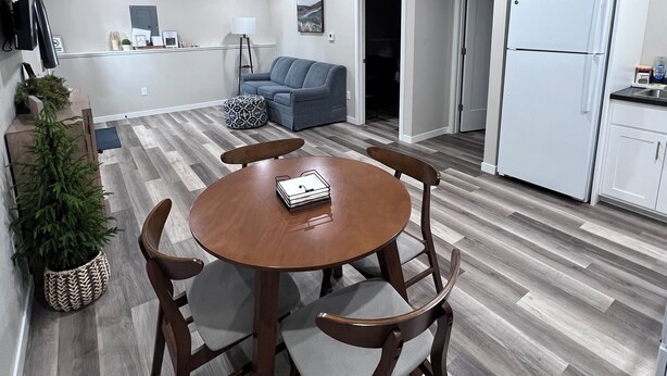 A modern living room with a dining table, chairs, a sofa, and a kitchen area with a refrigerator. - Home In Eddyville (Eddyville)