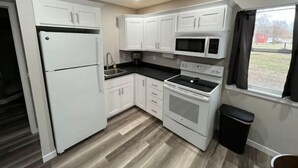 A compact kitchen with white cabinets, a refrigerator, a microwave, and an oven. - Home In Eddyville (Eddyville)