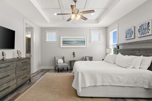 Ein Schlafzimmer mit Bett, Sessel, Schminktisch, Deckenventilator und Bildern an den Wänden.