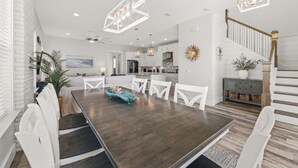 Un'area pranzo moderna con un tavolo in legno scuro, sedie bianche e un elemento decorativo al centro.