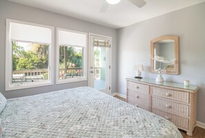 Ein Schlafzimmer mit einem großen Bett, einem Schminktisch, einem Spiegel und Blick auf einen Balkon mit Gartenmöbeln.