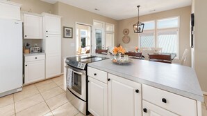 Una cocina moderna con armarios blancos, una estufa de acero inoxidable y una isla grande con una bandeja de flores.