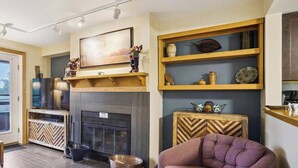 Una sala de estar con chimenea, estanterías de madera, televisor y sofá.