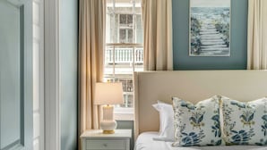 A bedroom with a bed, a nightstand, a lamp, a window with curtains, and a painting on the wall. - The Manor 93 - B Beautiful Three Bed Three Bath Close to King St. (Charleston)