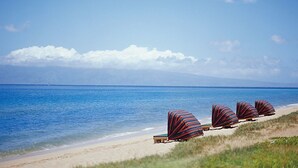 A beach with lounge chairs and umbrellas, a clear sky, and a calm sea.