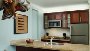 A kitchen with a granite countertop, stainless steel appliances, wooden cabinets, and a bar seating area.