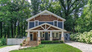 A two-story house with a front porch, a covered entryway, and a brick staircase leading to the door. - View Street Retreat | Pet Friendly, Fenced Yard, Walk to Town! (Black Mountain)