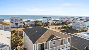 A coastal residential area with houses, a clear sky, and a view of the ocean.