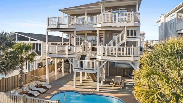 A multi-level house with a pool, outdoor seating, and a staircase connecting the levels.