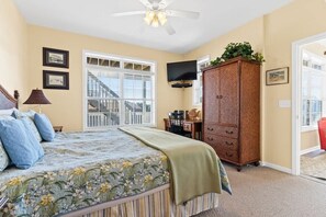 Ein Schlafzimmer mit Bett, Fernseher, Schrank und Fenster mit Blick auf eine Treppe.