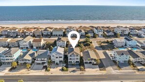A coastal residential area with houses, a beach, and a road.