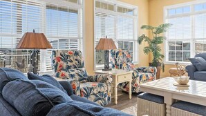 A living room with a sofa, armchairs, a coffee table, and a potted plant.