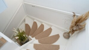 A staircase with a modern design, featuring a geometric pattern on the steps and a small potted plant on the landing. - Syltoase - 3-zimmer App. für 4 Personen mit Terrasse, Stellplatz, Wlan. Haustier Erlaubt (Westerland)