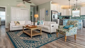 A living room with a white sofa, a patterned rug, and a wooden coffee table. - Tidewater East | Gulf-Side Comfort & Style (Dauphin Island)