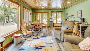 A cozy cabin interior with a dining area, a living room with a sofa and chairs, and a kitchen area. - Pokegama Lake Vacation Rental w/ Shared Boat Dock! (Grand Rapids)