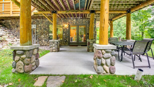 A covered patio area with stone pillars, a stone wall, and a seating area with a table and chairs. - Pokegama Lake Vacation Rental w/ Shared Boat Dock! (Grand Rapids)