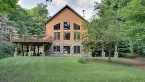 A log cabin with a stone foundation, a wooden deck, and a stone chimney. - Pokegama Lake Vacation Rental w/ Shared Boat Dock! (Grand Rapids)