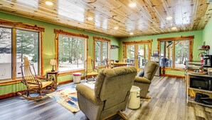 A cozy interior with wooden ceiling, large windows, a dining area, and a kitchen. - Pokegama Lake Vacation Rental w/ Shared Boat Dock! (Grand Rapids)