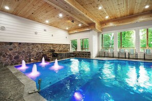 Une piscine dotée de fontaines intégrées, de murs en pierre et d’un plafond en bois.