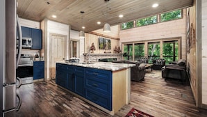 Una cocina moderna con una isla grande, pisos de madera y un comedor con vista al exterior.