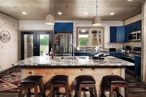 A modern kitchen with a large island, blue cabinets, stainless steel appliances, and a wooden ceiling. - Sierra Cascades - Indoor Pool, Driving Simulator & Mountain Game Loft (Sevierville)