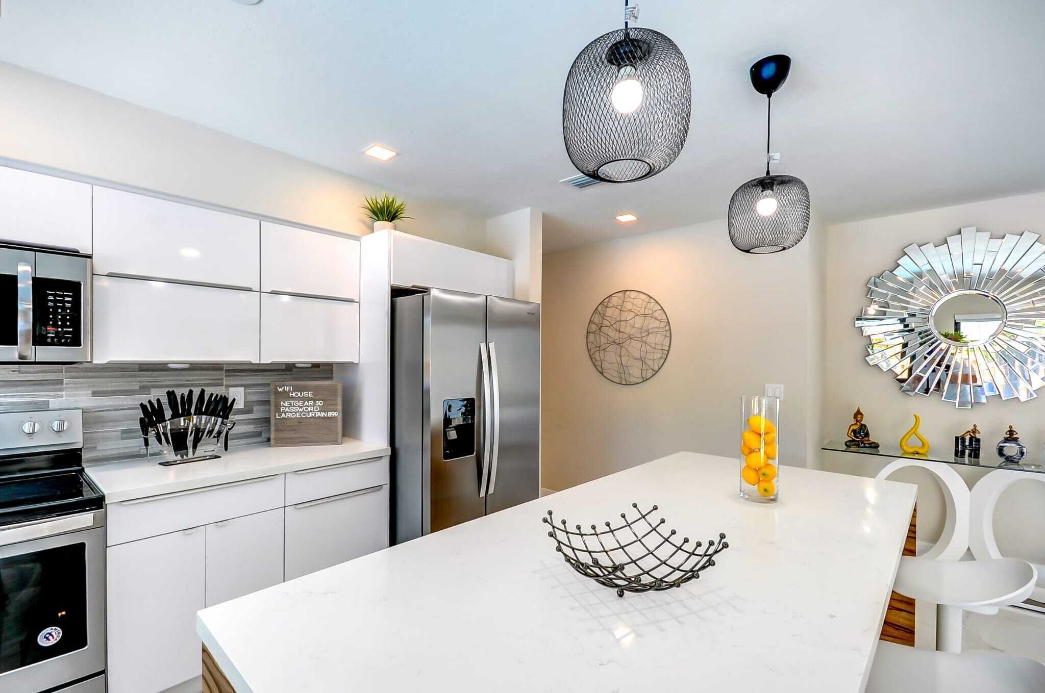 A modern kitchen with white cabinetry, stainless steel appliances, and decorative wall art.
