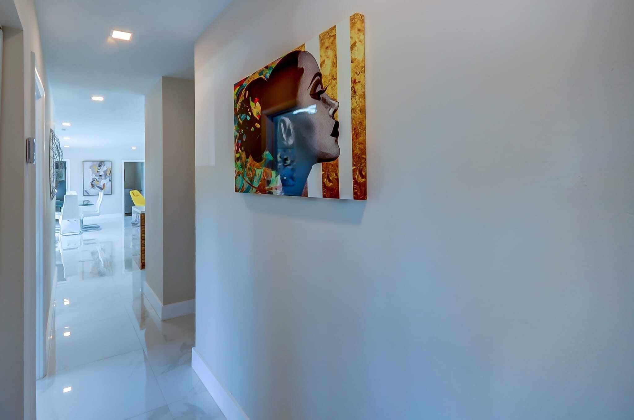 A hallway with a modern art piece on the wall, a clean floor, and a bright ceiling.