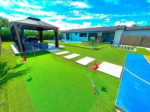A backyard with a putting green, a gazebo, and a swimming pool. - Tropical Miami/Heated pool/Basketball Court/Pin Pong Table/Patio Chess/Mini Golf (Miami)