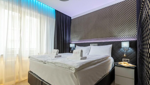 Una habitación de hotel moderna con una cama grande, una mesita de noche con lámpara y una pared con diseño.