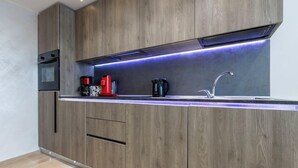 Una cocina moderna con armarios de madera, un lavamanos de acero inoxidable y un horno empotrado.