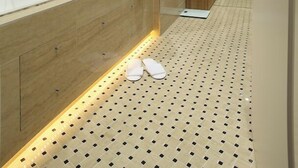A modern bathroom with a glass shower enclosure, a wooden vanity, and a patterned floor.