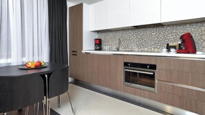 A modern kitchen with a stone backsplash, a coffee maker, and a red appliance on the countertop.