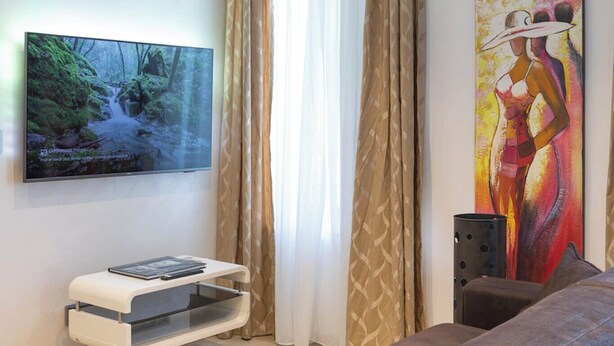 Una sala de estar moderna con un televisor de pantalla plana, un sofá, una mesa de centro y un cuadro en la pared.