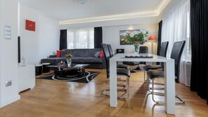 A modern living room with a sofa, coffee table, and dining area.