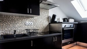 Una cuina moderna amb una façana de pedra, un taulell negre i un finestral a la teulada.