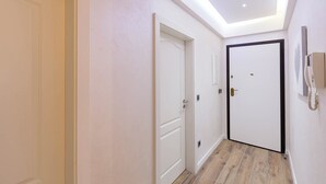 A hallway with a skylight, white doors, and a telephone on the wall.