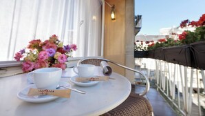 A table with a white cup, saucer, and a tea bag on a tray, with a bouquet of flowers in the background.