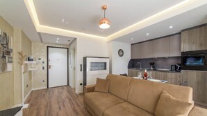 Ein modernes Wohnzimmer mit einer Couch, einer Küchenzeile mit Geräte und einer Tür zu einem weiteren Raum.