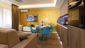 Una sala de estar moderna con un sofá, una mesa de comedor con sillas y una zona de cocina con refrigerador y horno.