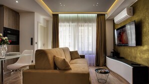 A modern living room with a sofa, a dining table, and a TV. - Carlotta -33 Appartement avec Balcon (Luxembourg)
