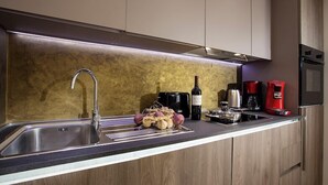 A modern kitchen with a stainless steel sink, a wine bottle, a coffee maker, and a kettle on the counter. - Carlotta -33 Appartement avec Balcon (Luxembourg)